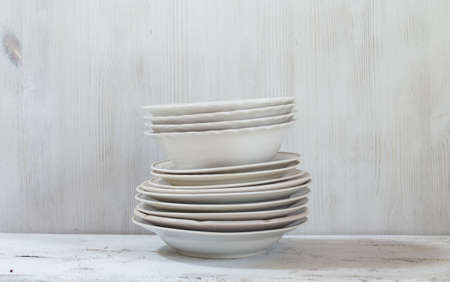 stack of white plates on wooden white tableの写真素材