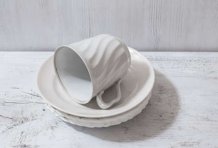 stack of white plates and cup on wooden white tableの写真素材