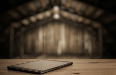 tablet on desk in old wooden interior with light bulbの写真素材