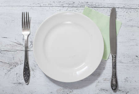 antique fork, knife and plate on white wooden tableの写真素材