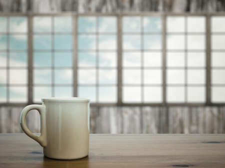 mug on wooden table in old room with big windowsの写真素材