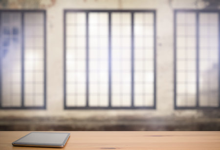 tablet on wooden table in old room with big windows