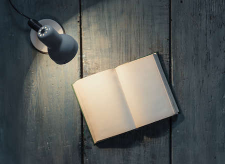 lamp and opened book on wooden tableの写真素材