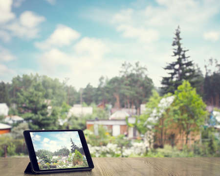 tablet on wooden table with nature countryside blurred backgroundの写真素材