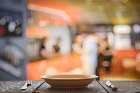 empty plate with fork and knife on wooden table in the restaurantの写真素材