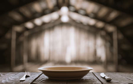 empty plate with fork and knife on table in old wooden roomの写真素材