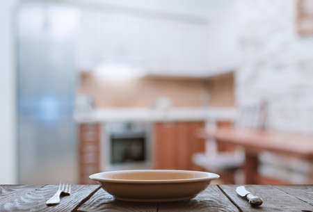 empty plate with fork and knife on wooden table in the kitchenの写真素材