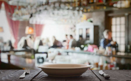 empty plate with fork and knife on wooden table in the restaurantの写真素材