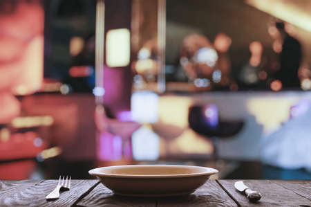 empty plate with fork and knife on wooden table in the restaurantの写真素材
