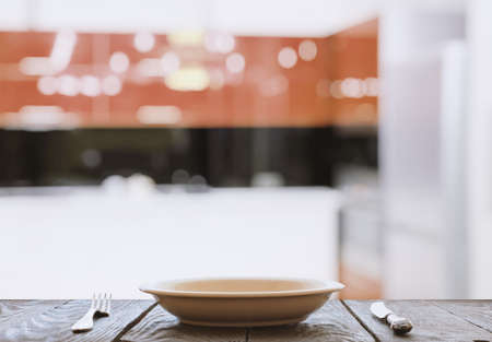 empty plate with fork and knife on wooden table in the kitchenの写真素材