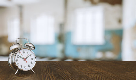 clock on wooden table in room with big windows