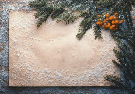 holiday decoration with paper, snow, bells, green branch and rowan on wooden frozen table, christmas backgroundの写真素材