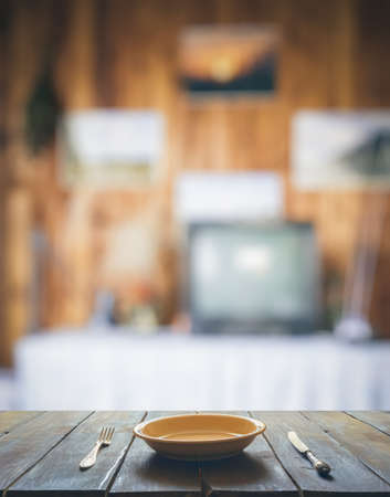 empty plate with fork and knife on wooden table in the living room with TVsetの写真素材