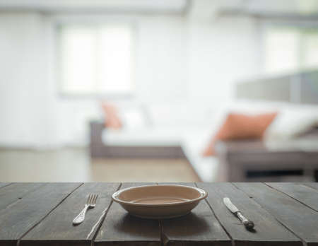empty plate with fork and knife on wooden table in the living roomの写真素材