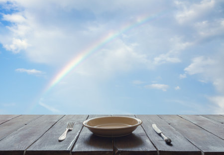 empty plate with fork and knife on wooden table, sky background