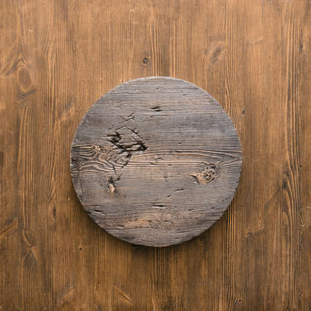 grunge empty round wooden plate on old wooden table, background with copyspaceの写真素材