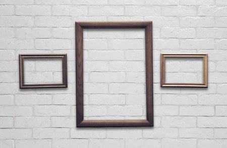 old photo frames on white brick wall