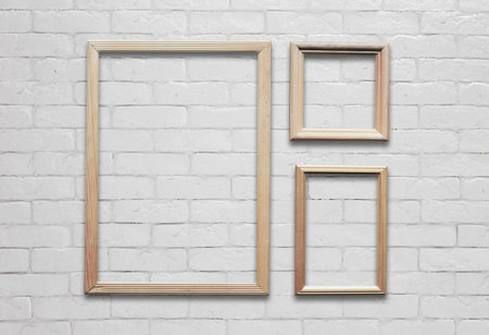 old photo frames on white brick wall