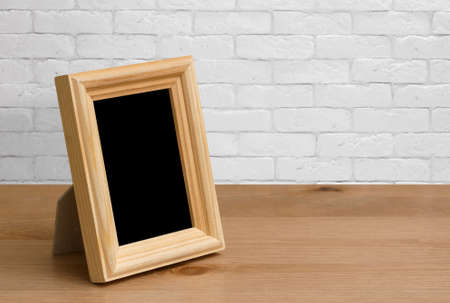 old photo frame on the wooden table, white brick wallの写真素材