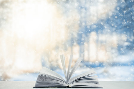 open book on the table, winter woodland background with falling snowの写真素材