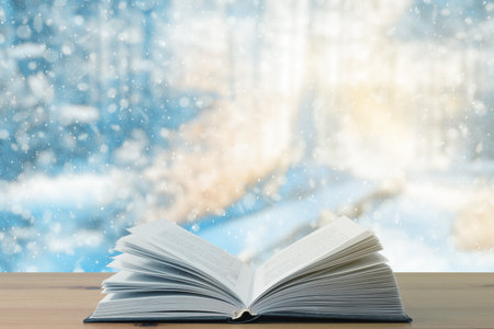 open book on the table, winter woodland background with falling snowの写真素材