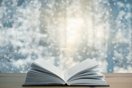 open book on the table, winter woodland background with falling snowの写真素材