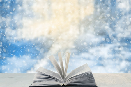 open book on the table, winter woodland background with falling snowの写真素材