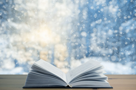 open book on the table, winter woodland background with falling snowの写真素材