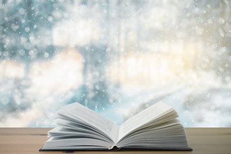 open book on the table, winter woodland background with falling snowの写真素材