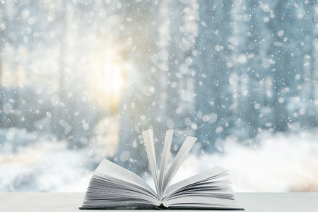 open book on the table, winter woodland background with falling snowの写真素材