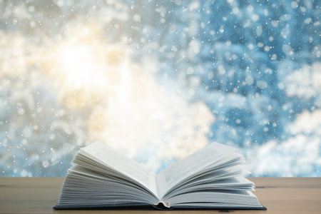 open book on the table, winter woodland background with falling snowの写真素材