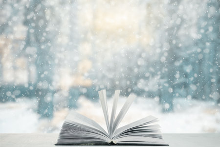 open book on the table, winter woodland background with falling snowの写真素材