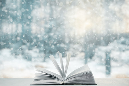 open book on the table, winter woodland background with falling snowの写真素材