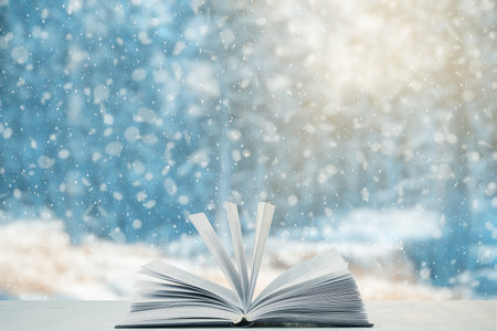 open book on the table, winter woodland background with falling snowの写真素材