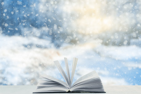 open book on the table, winter woodland background with falling snowの写真素材