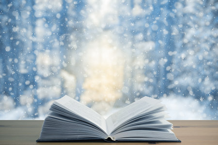 open book on the table, winter woodland background with falling snowの写真素材