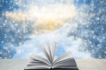 open book on the table, winter woodland background with falling snowの写真素材
