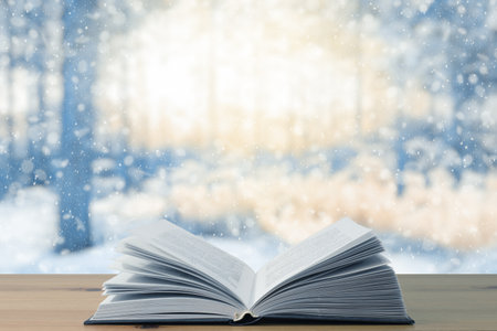 open book on the table, winter woodland background with falling snowの写真素材