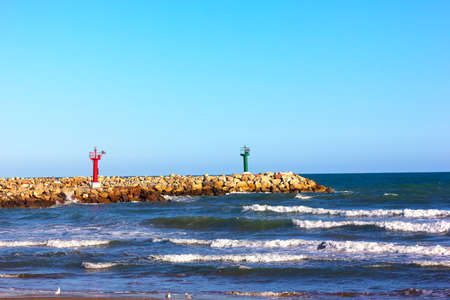 Red and green lighthouses on marine cape  Marine Cape with colorful lighthouses and sea waves の写真素材