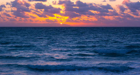 Sunset over the ocean with violet clouds. Scenic sunset over the ocean.の写真素材