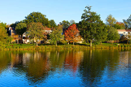 A waterfront townhouses among colorful trees at dawn in Washington DC. Picturesque autumn foliage with reflections in the lake in North Virginia.の写真素材