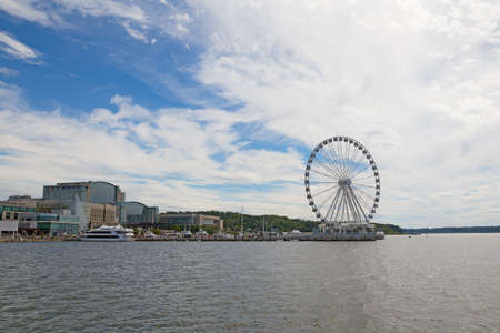 Panorama of National Harbor with Ferris on the pier, Maryland, USA. National Harbor waterfront under blue skies with scenic clouds.の写真素材