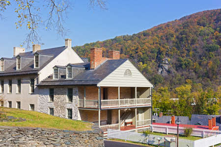 Houses on the street of historic town in Harpers Ferry National Historical Park, West Virginia, USA. The town in autumn colors with Blue Ridge Mountains on background.の写真素材