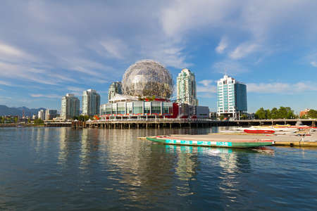 City skyline at False Creek with Science World and boats pier in Vancouver. Sunny day in Vancouver with high cloud and mountain on horizon.のeditorial素材