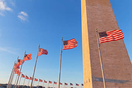 Washington Monument and American flags before sunset in US capital. Obelisk built to commemorate George Washington, the first President of the United States.の写真素材