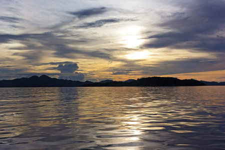 Sunset over the mountains on the horizon on Coron Island, Philippines. Quiet sea at sunset with...
