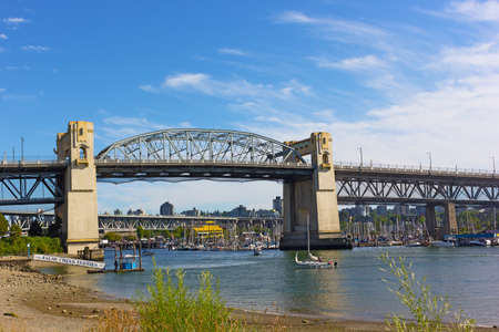 VANCOUVER, CANADA â JUNE 30: False Creek ferries stop near historic Burrard Bridge on June 30, 2017 in Vancouver. Tourists prefer a short boat ride to get to a famous public market located on Granville Island.のeditorial素材
