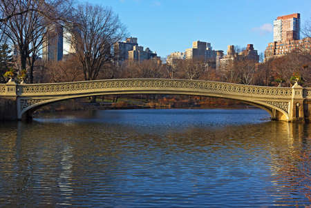 Bow Bridge at sunny morning in Central Park, New York City. Landscape of the park with lake and urban Manhattan skyscrapers on horizon in winter.  の写真素材