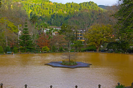 Park with thermal pool on Azores, Portugal. Morning sun touches mountains surrounding park with tropical plants and floral gardens.の写真素材