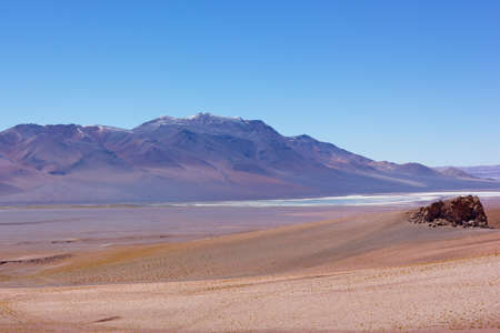 Intense pastel colored landscape of Atacama Desert landscape after sunrise, Chile. High altitude desert and volcanic mountains colored by rising sun in light lilac hue on horizon.の写真素材